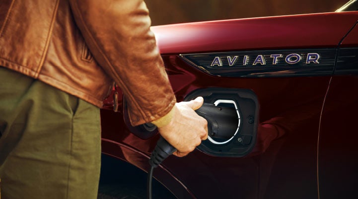A hand is shown plugging in the charger into the charging port of a 2021 Lincoln Aviator | Empire Lincoln of Huntington in Huntington NY