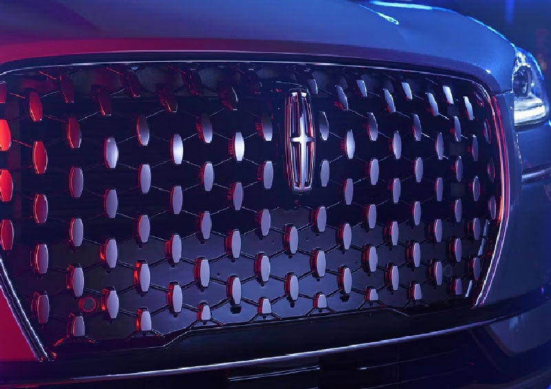 The grille of a 2025 Lincoln Corsair® SUV reflects neon light at night. | Empire Lincoln of Huntington in Huntington NY