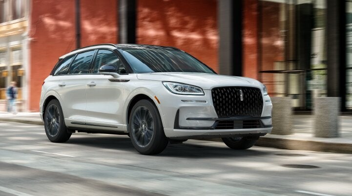 A white 2025 Lincoln Corsair® SUV with the Jet Appearance Package is being driven through a city.| Empire Lincoln of Huntington in Huntington NY