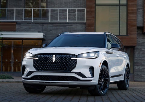 A 2026 Lincoln Aviator® Reserve model is shown with the available Jet Appearance Package parked near a restaurant. | Empire Lincoln of Huntington in Huntington NY