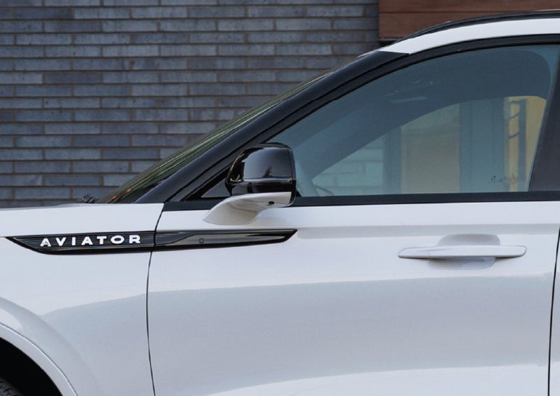 The driver’s side door and fender badging of a white 2026 Lincoln Aviator® SUV are showcased. | Empire Lincoln of Huntington in Huntington NY