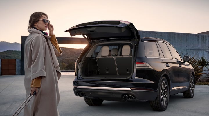 A woman approaches a 2026 Lincoln Aviator® SUV with its rear liftgate open. | Empire Lincoln of Huntington in Huntington NY