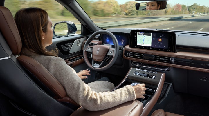 A 2026 Lincoln Aviator® SUV is being driven hands-free on a highway near a forest | Empire Lincoln of Huntington in Huntington NY
