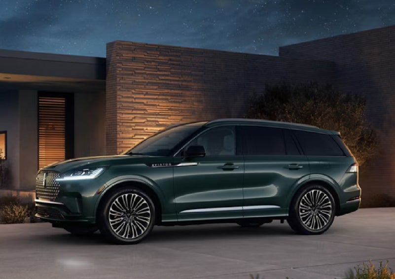 A green 2027 Lincoln Aviator® SUV is parked outside a contemporary home. | Empire Lincoln of Huntington in Huntington NY