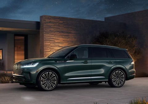 A green 2027 Lincoln Aviator® SUV is parked outside a contemporary home. | Empire Lincoln of Huntington in Huntington NY