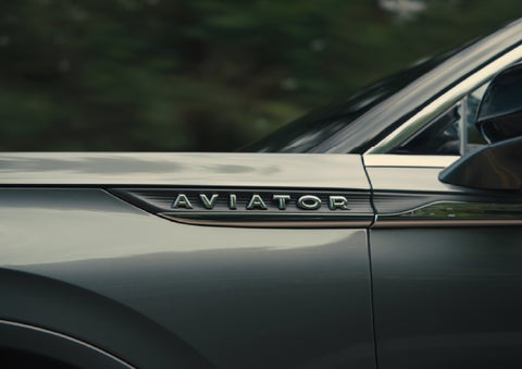 The driver’s side door and fender badging of a gray 2027 Lincoln Aviator® SUV are showcased. | Empire Lincoln of Huntington in Huntington NY