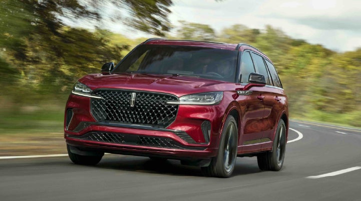A 2027 Lincoln Aviator® SUV is being driven on a country road | Empire Lincoln of Huntington in Huntington NY