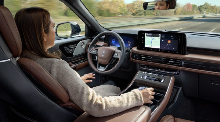 A 2027 Lincoln Aviator® SUV is being driven hands-free on a highway lined with trees. | Empire Lincoln of Huntington in Huntington NY