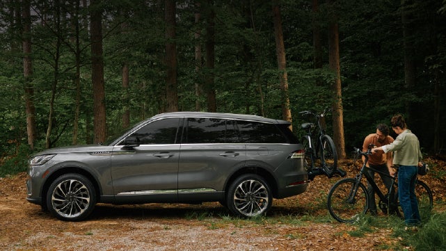 A father and son load e-bikes on a bike rack attached to a 2027 Lincoln Aviator® SUV. | Empire Lincoln of Huntington in Huntington NY