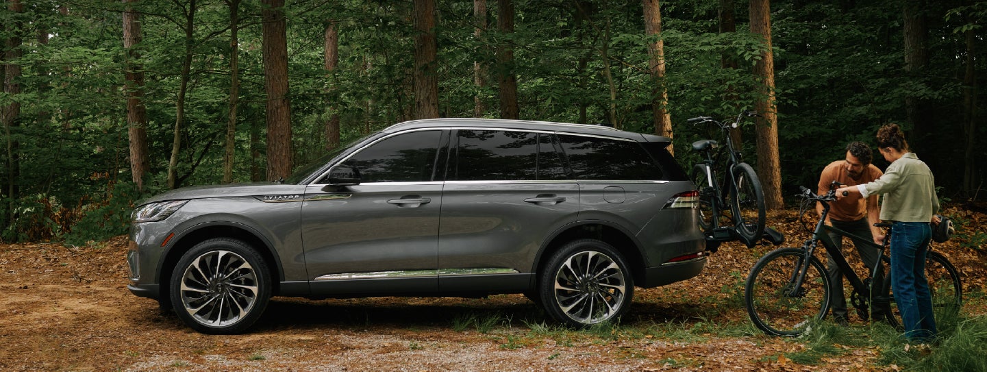 A father and son load e-bikes on a bike rack attached to a 2027 Lincoln Aviator® SUV. | Empire Lincoln of Huntington in Huntington NY